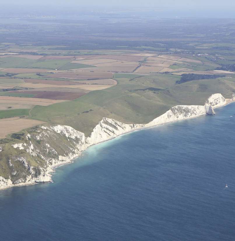 Aerial view of a stretch of the Jurassic Coast including blue sea, rugged cliffs and countryside