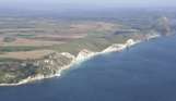 Aerial view of a stretch of the Jurassic Coast including blue sea, rugged cliffs and countryside