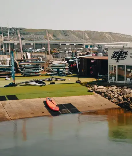 A windsurfing and watersports centre by the water with various watersports equipment