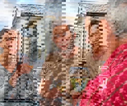 A couple sat with an older man at an outside table all drinking wine