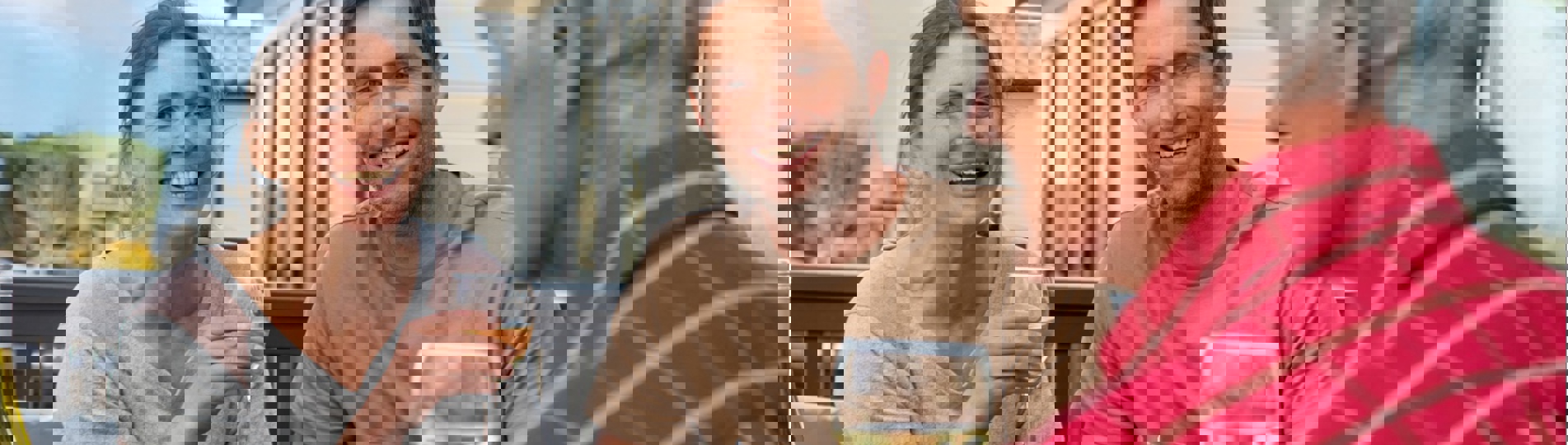 A couple sat with an older man at an outside table all drinking wine