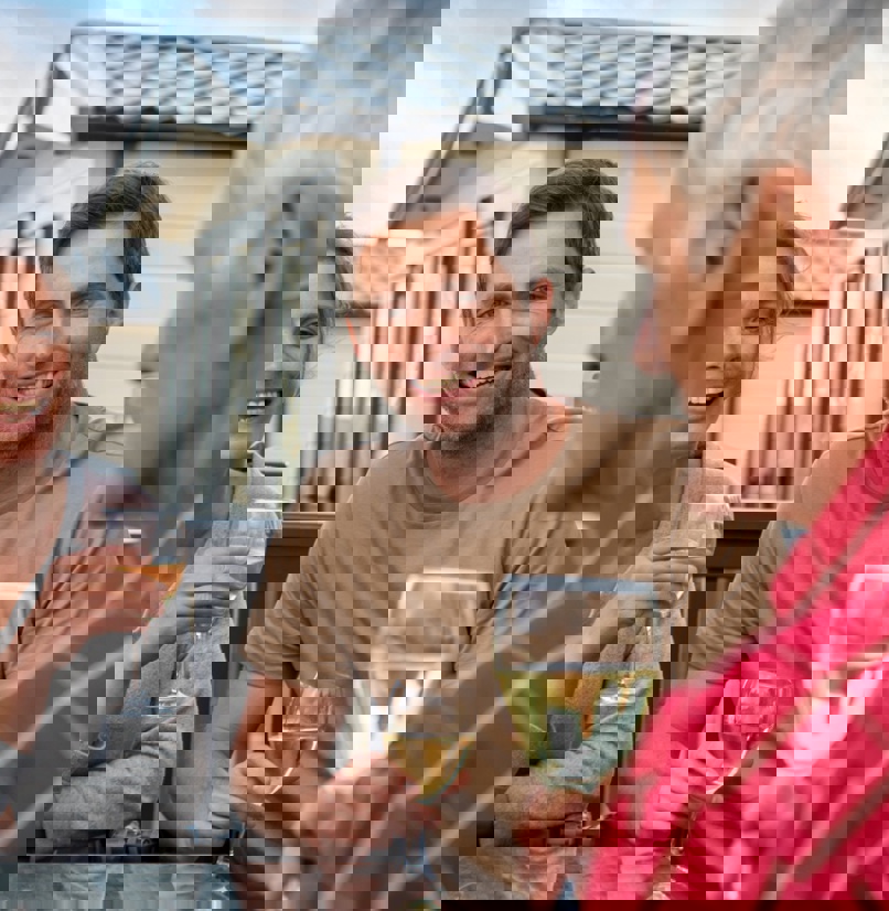 A couple sat with an older man at an outside table all drinking wine