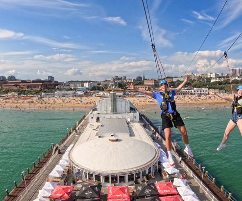 Two people on a zip line over Bournemouth Pier
