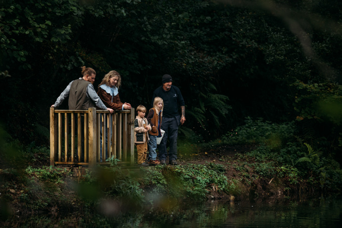A family of four in the woodland by lakes with a team member