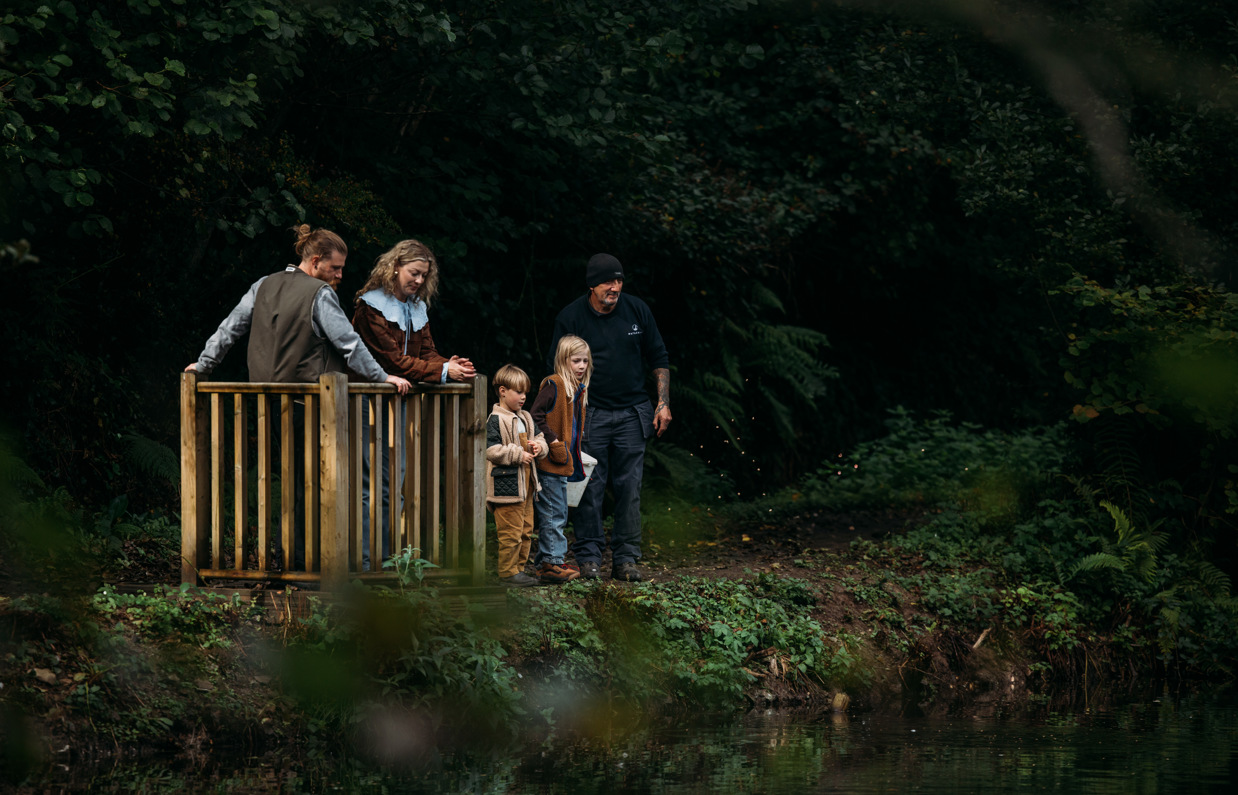 A family of four in the woodland by lakes with a team member