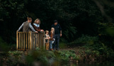 A family of four in the woodland by lakes with a team member