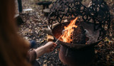 Toasting a marshmallow over a fire pit in the woods