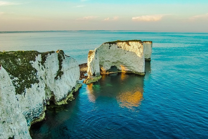 A white chalk formation of cliffs dropping into the blue sea with striking skies