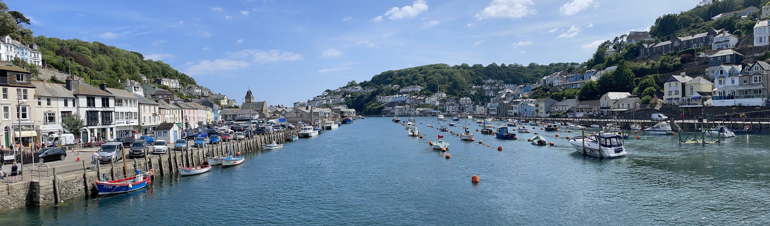 A tranquil harbour with various boats and buildings to explore on a sunny, blue sky day