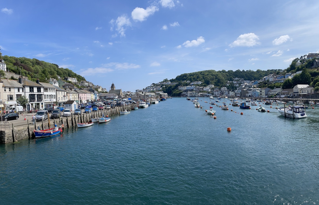 A tranquil harbour with various boats and buildings to explore on a sunny, blue sky day