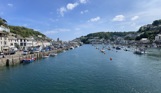A tranquil harbour with various boats and buildings to explore on a sunny, blue sky day