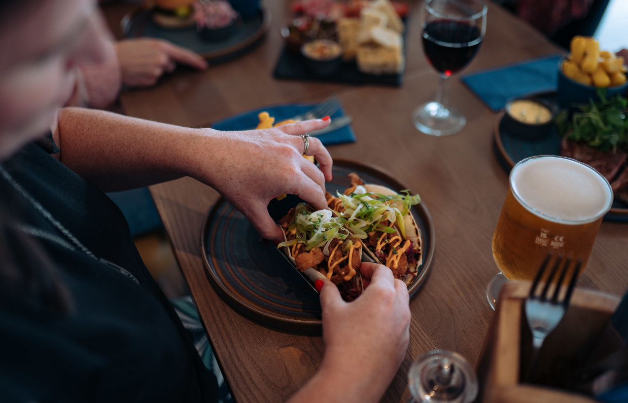 Fish tacos being picked up by a lady sat at a table in Drift Bar & Grill