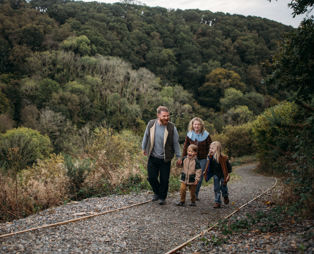 A family of four walking up a nature path among woodland