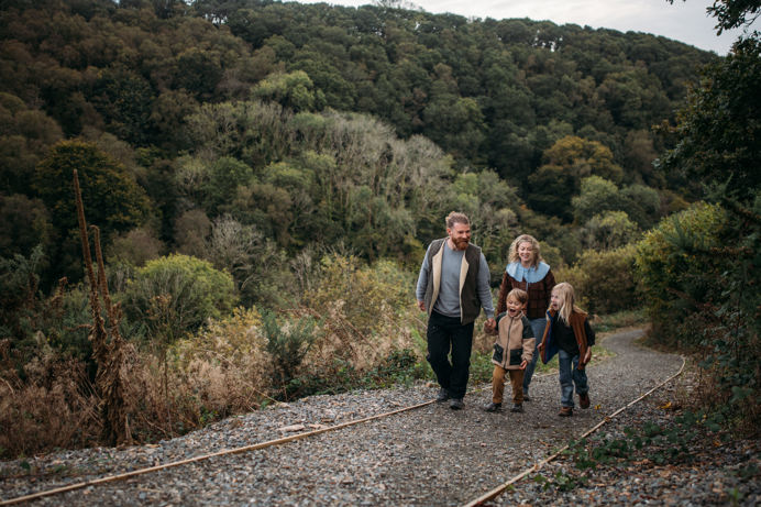 A family of four walking up a nature path among woodland