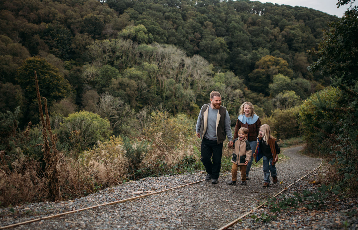 A family of four walking up a nature path among woodland