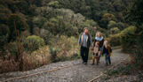 A family of four walking up a nature path among woodland