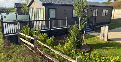 External of a luxury lodge on pitch with decking and hot tub