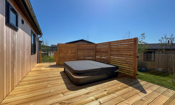 External of a luxury lodge on pitch with decking and hot tub