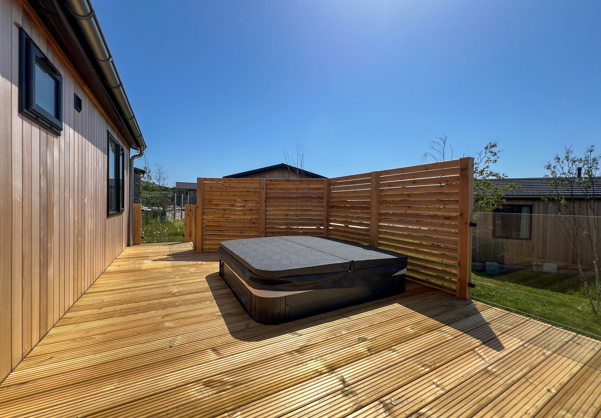 External of a luxury lodge on pitch with decking and hot tub