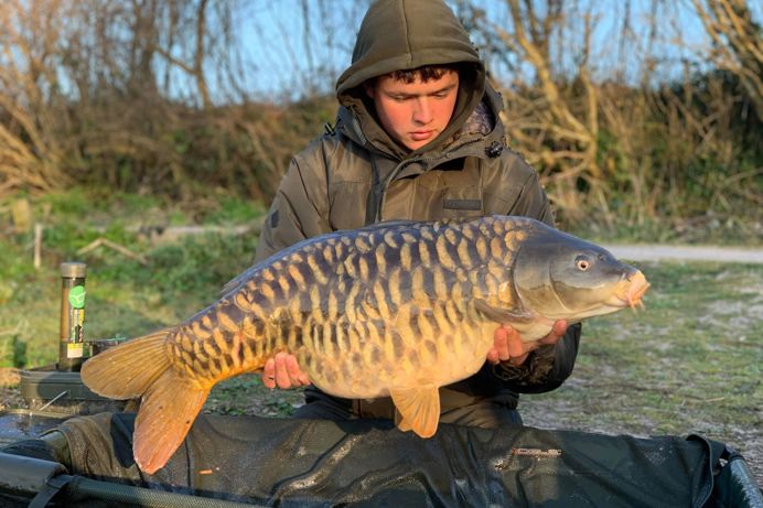 A man with a large fish caught beside Bake Lake