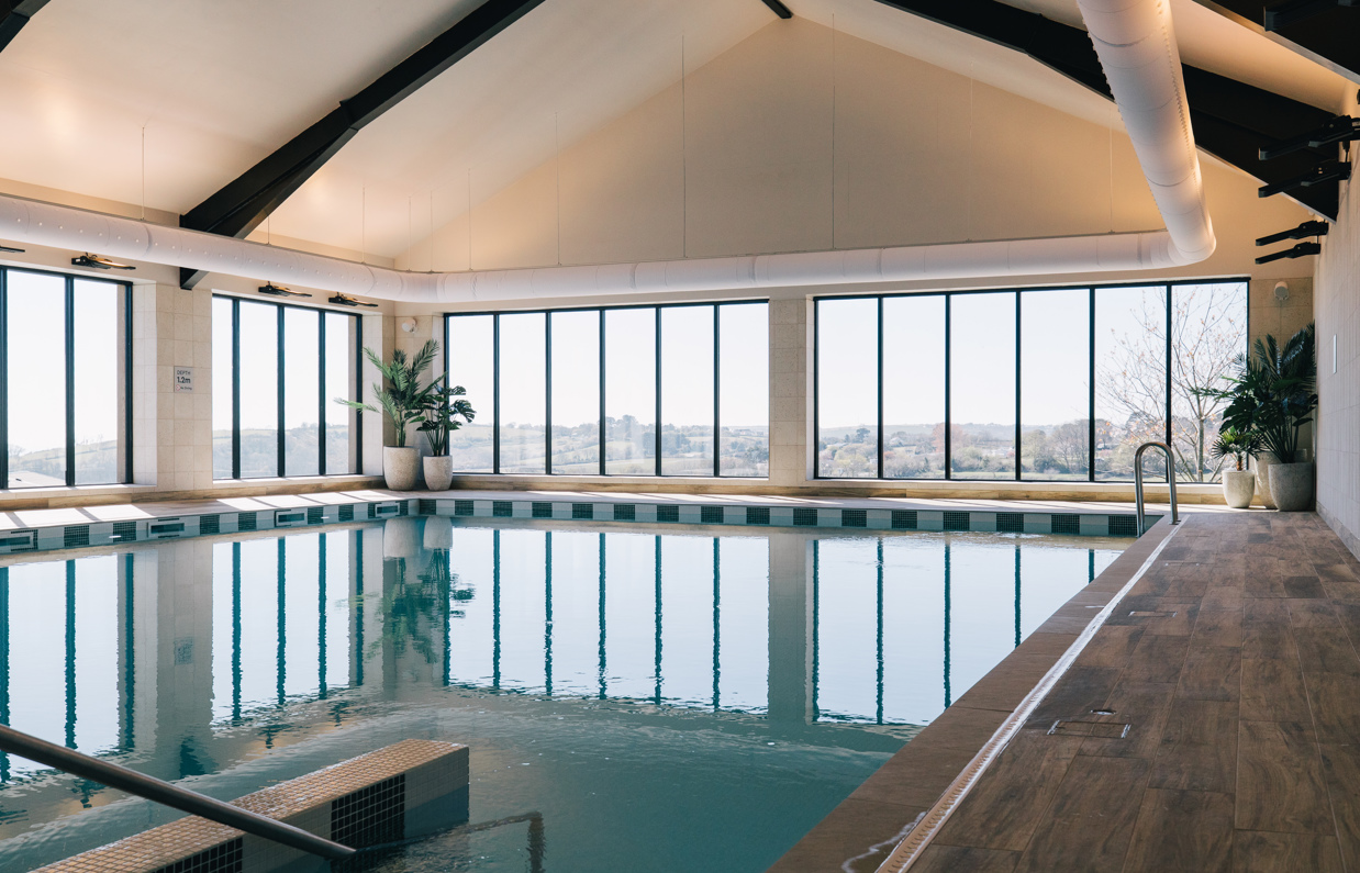 Indoor heated pool within a barn style building with countryside and valley views
