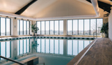 Indoor heated pool within a barn style building with countryside and valley views