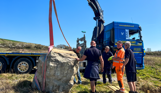 Installation of a stone sculpture in a field with blue skies