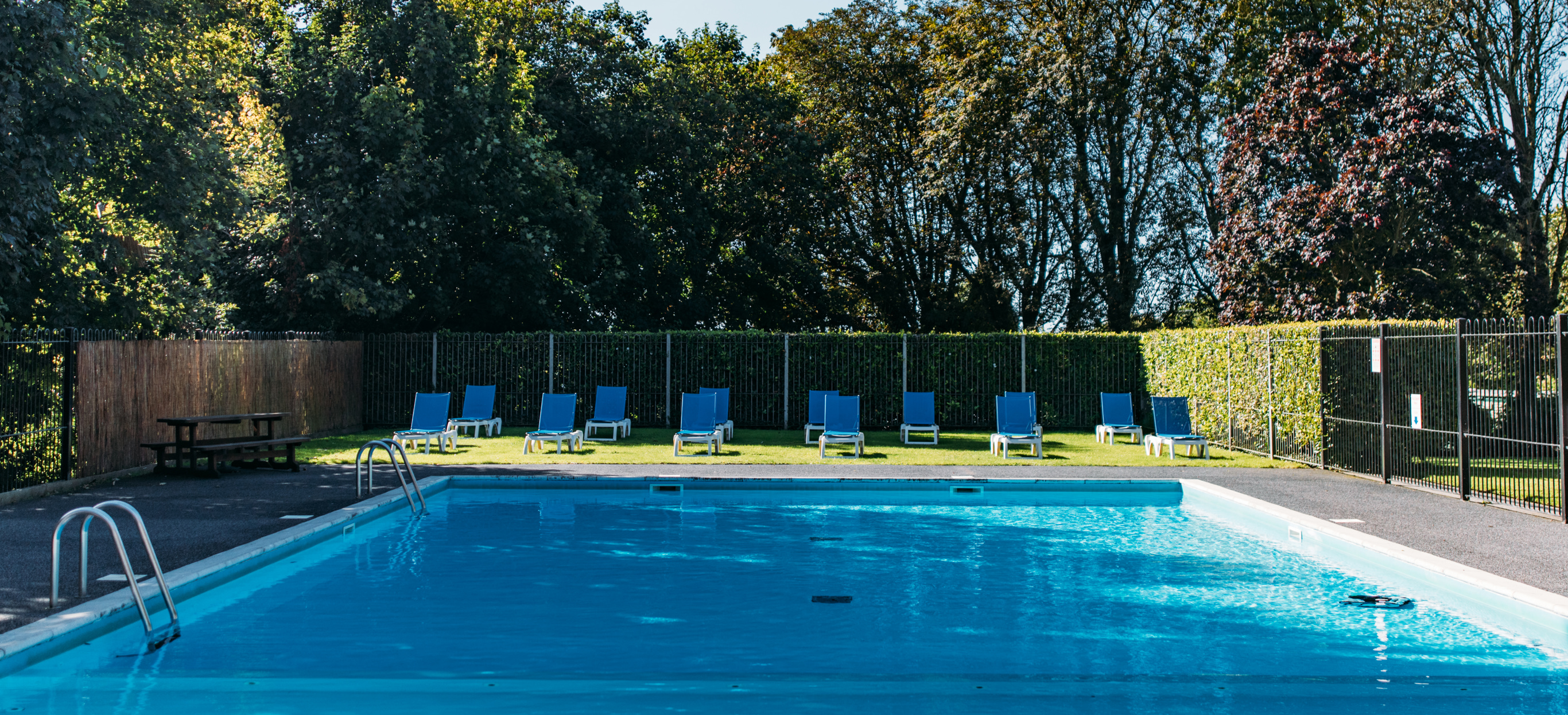 An outdoor pool with a sun terrace and sun loungers on a sunny day
