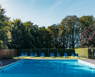 An outdoor pool with a sun terrace and sun loungers on a sunny day