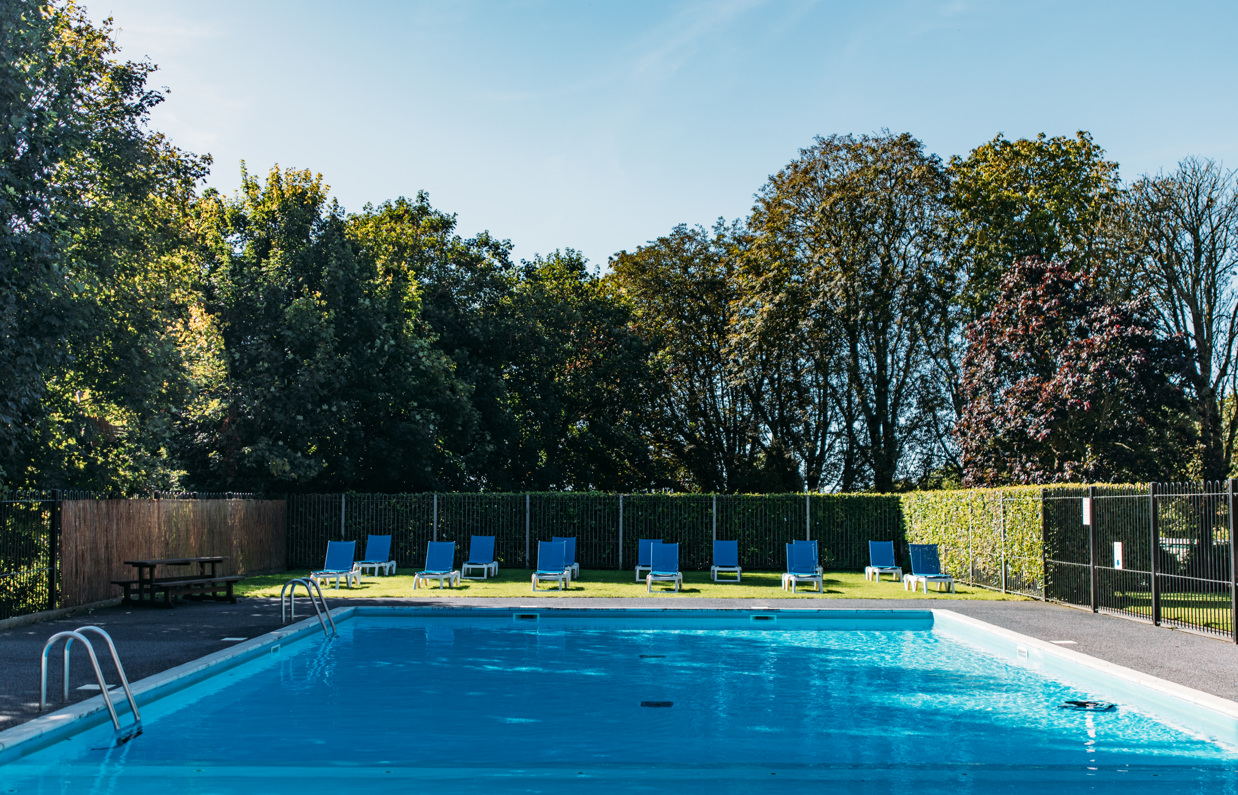 An outdoor pool with a sun terrace and sun loungers on a sunny day