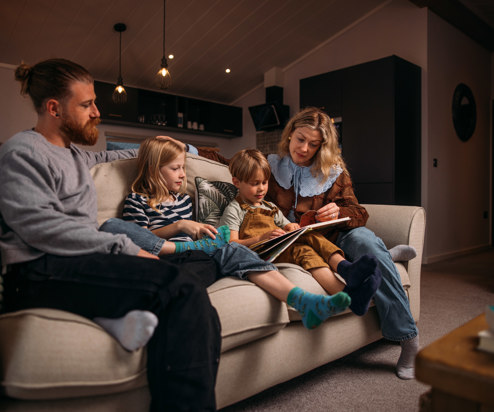 Family cosily reading stories on sofa in holiday home