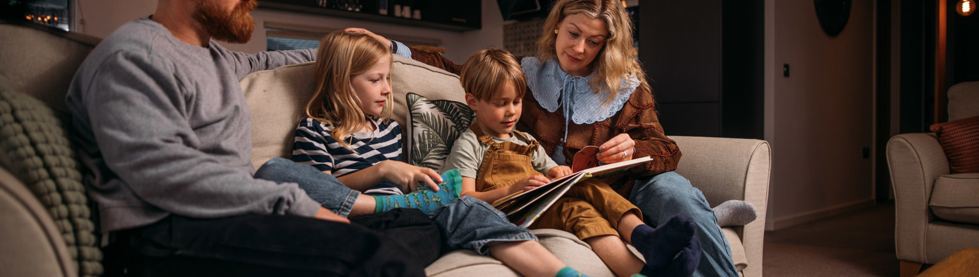 Family cosily reading stories on sofa in holiday home