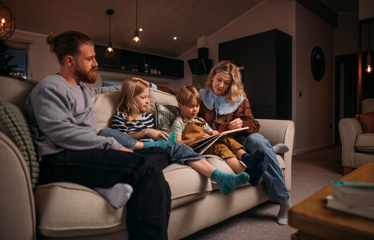 Family cosily reading stories on sofa in holiday home