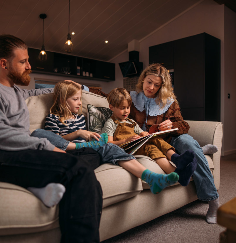 Family cosily reading stories on sofa in holiday home