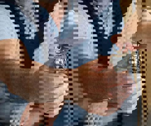 A woman's hand passing a set of keys to a man whose hand is stretched out to grab the keys