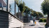 A family of three walking down a road on a lodge park surrounded by holiday lodges and woodland on a sunny, blue sky day