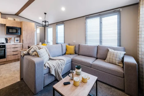 Cosy lounge with L-shaped sofa next to open-plan kitchen diner