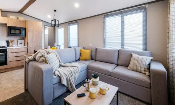 Cosy lounge with L-shaped sofa next to open-plan kitchen diner