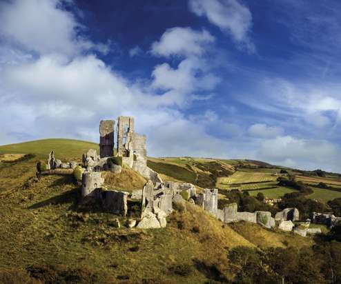 The ruins of a castle perched atop a hill among the Purbeck Hills