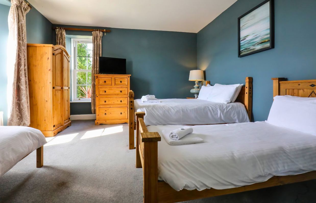 Internal of a manor house bedroom with double bed, two twin beds and tv