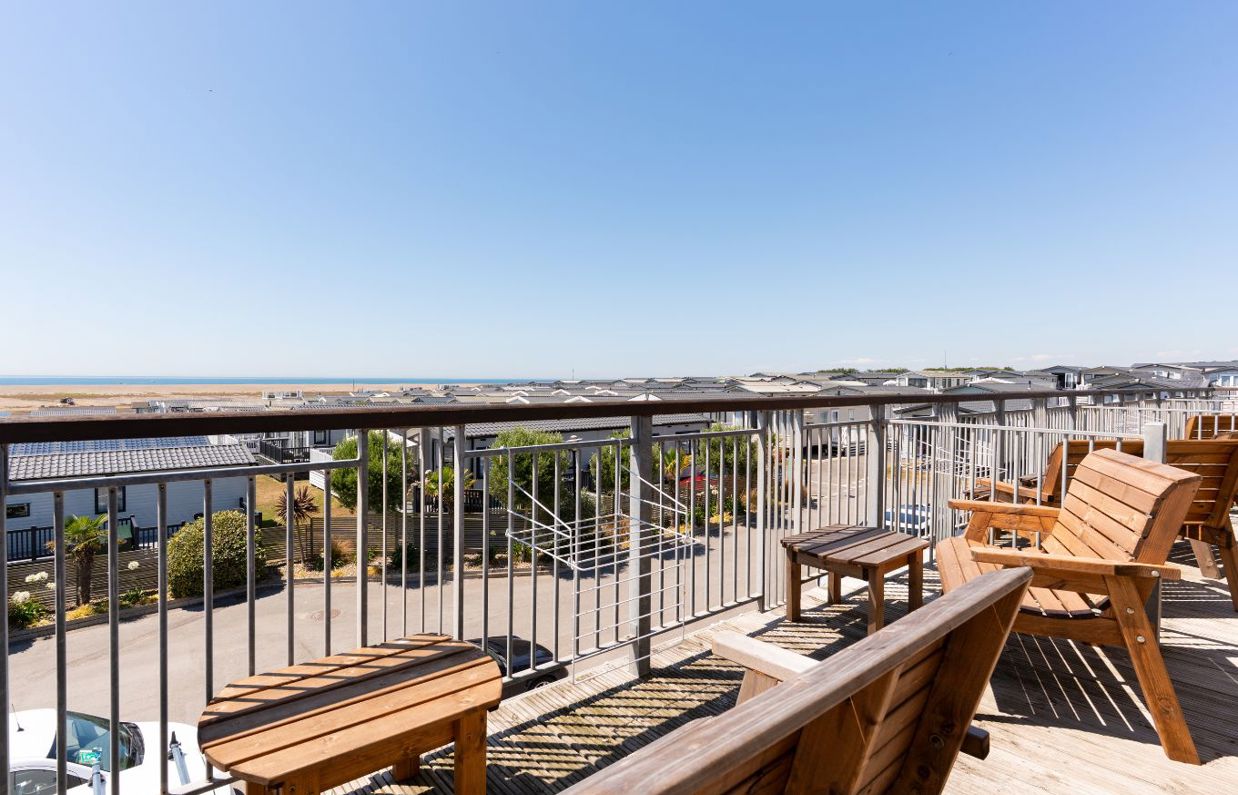 Views from the balcony of Chesil Beach apartments across the holiday park out to sea with outdoor furniture in the foreground