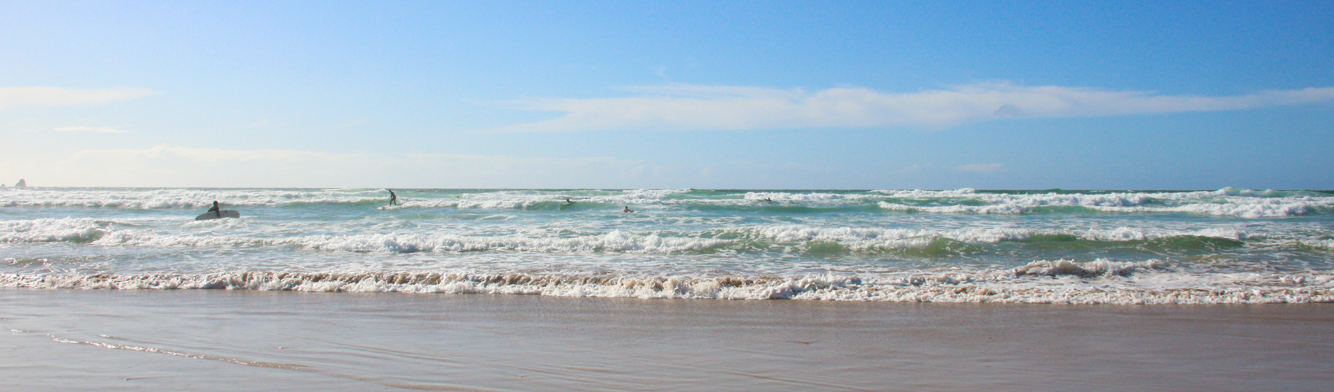 Surf-ready waves on a sandy beach on a sunny, blue sky day
