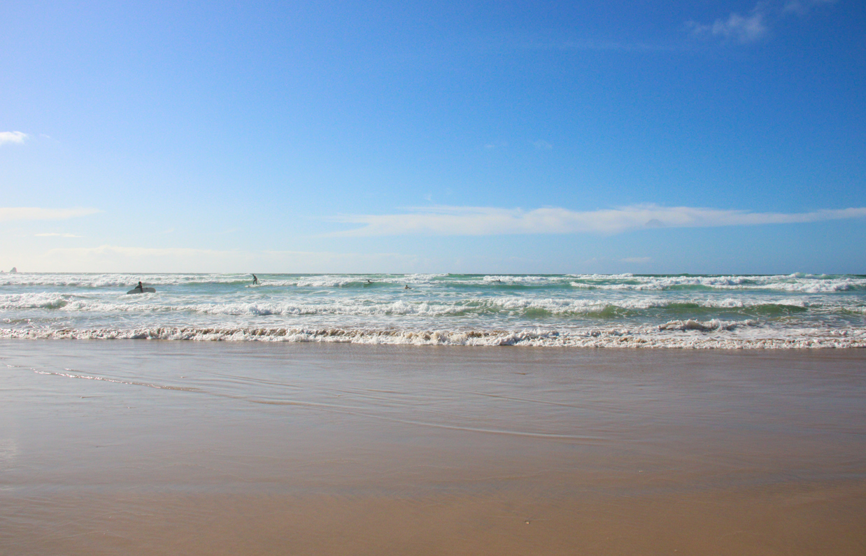 Surf-ready waves on a sandy beach on a sunny, blue sky day