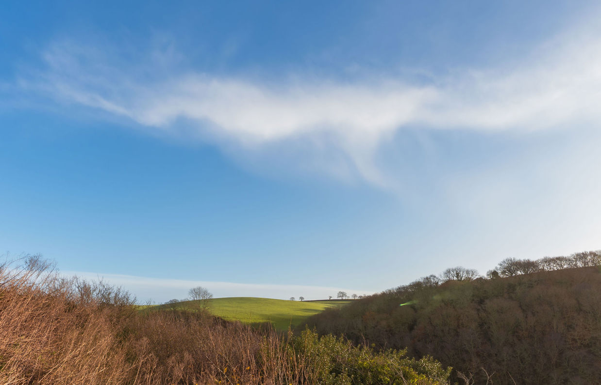 Wispy clouds and wooded hills