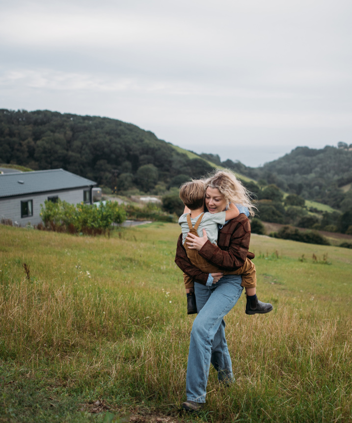 Woman carrying child up hill with valley views behind