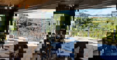 Free standing dining table and chairs with view of large decking and valley beyond