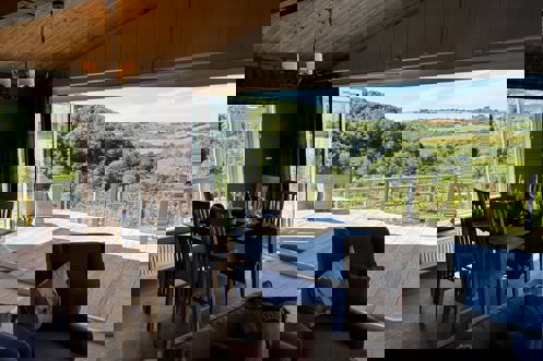 Free standing dining table and chairs with view of large decking and valley beyond