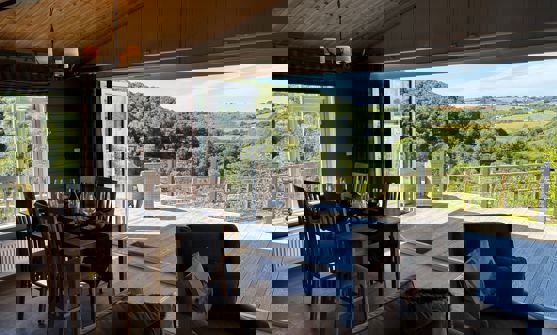 Free standing dining table and chairs with view of large decking and valley beyond