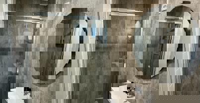 Shower room with grey cabinets and light wood flooring and concrete style tiles