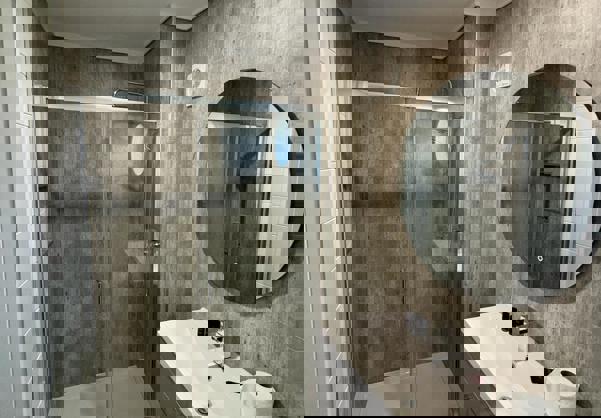 Shower room with grey cabinets and light wood flooring and concrete style tiles